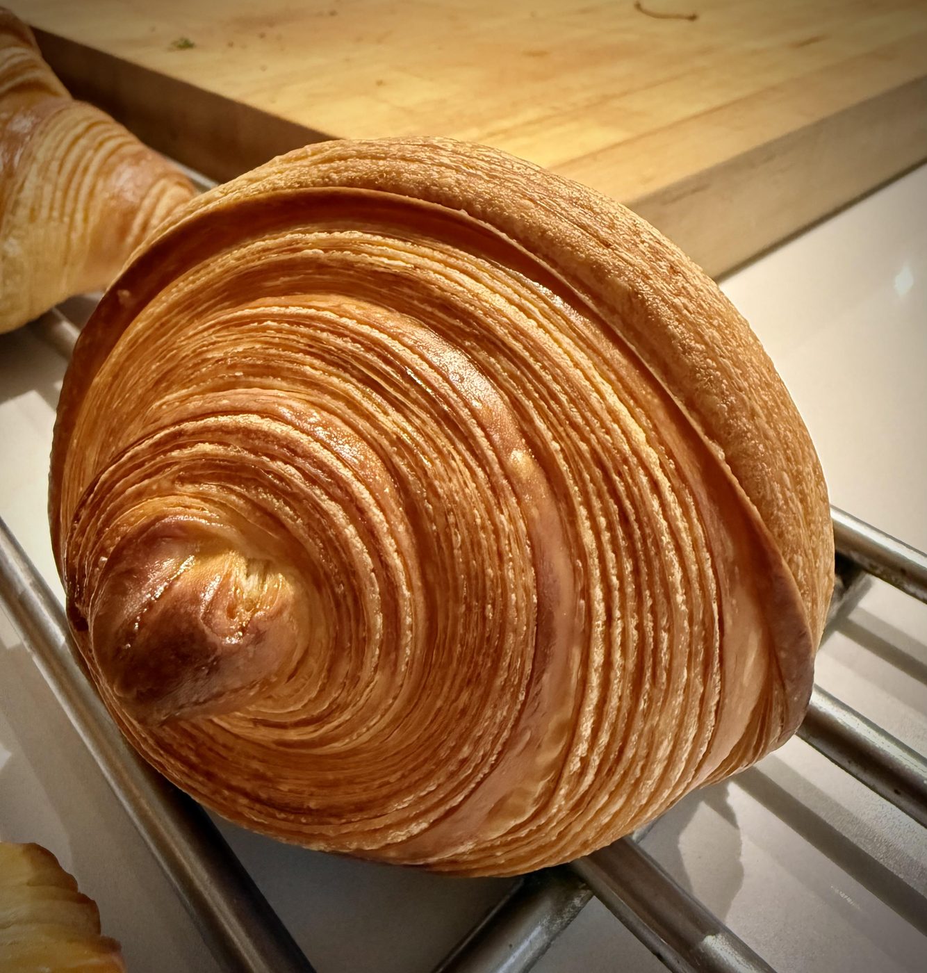 A single beautifully laminated croissant, top-down, with even glossy swirls