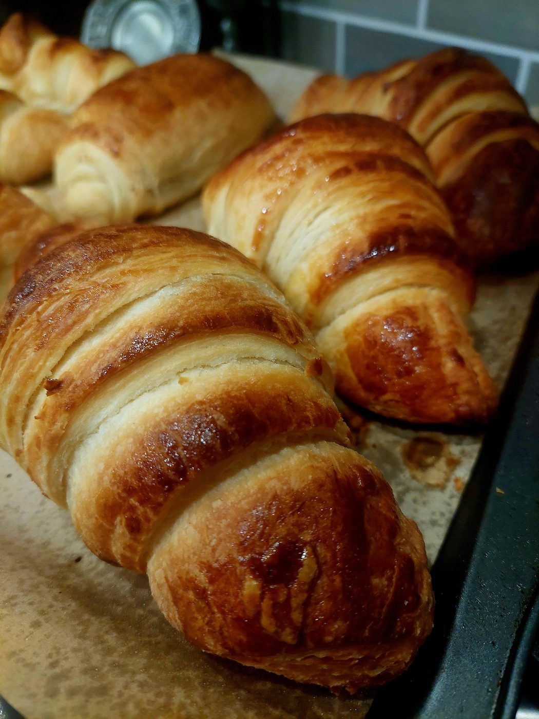 Deeply golden baked croissants cooling on parchment
